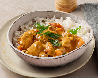 Bowl of curry with rice on a neutral background