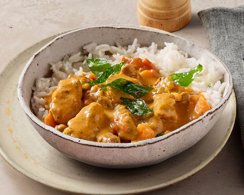 Bowl of curry with rice on a neutral background
