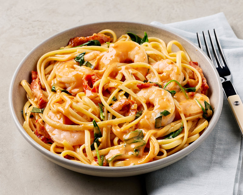  bowl of spaghetti with shrimp and vegetables on a beige tablecloth