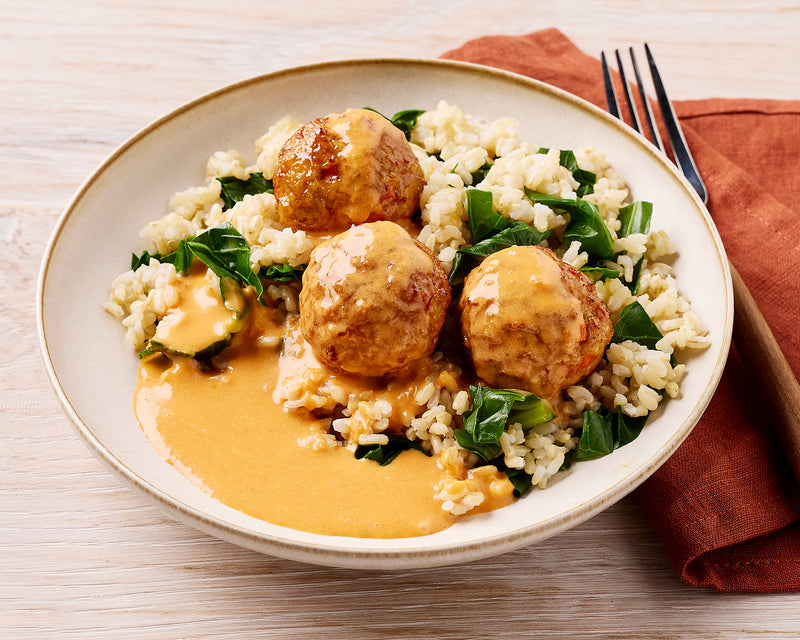 Plate of Thai meatballs with rice and greens on a wooden table
