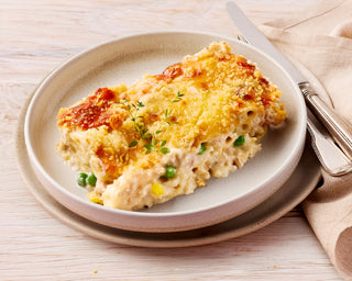 Cheesy Tuna casserole on a plate with a napkin and cutlery on a wooden table
