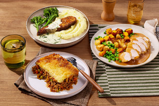 Three plates of food on a wooden table with glasses of water.
